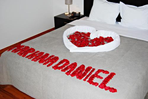 a bed with a heart made out of red roses at Hotel Quinta Progresso in Macieira de Cambra