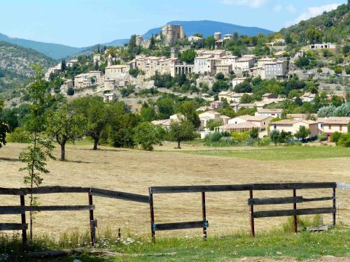 une clôture dans un champ avec une ville sur une colline dans l'établissement Studio Walla Confort Centre, à Montbrun-les-Bains