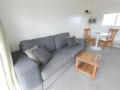 a living room with a gray couch and a table at Castle Court Motel in Wellsford