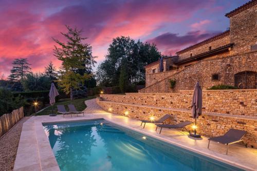 - une piscine en face d'un bâtiment avec un coucher de soleil dans l'établissement La Trappezienne, à Sarlat-la-Canéda
