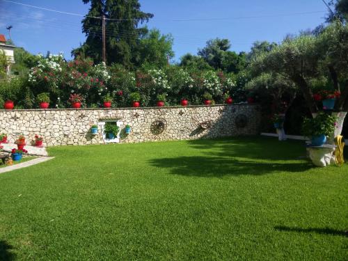 a garden with a stone wall and green grass at Grammatoula in Nikiana