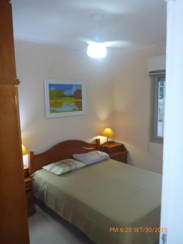 Un dormitorio con una cama y dos lámparas y una ventana. en Apartamento Capão Novo, en Capão da Canoa