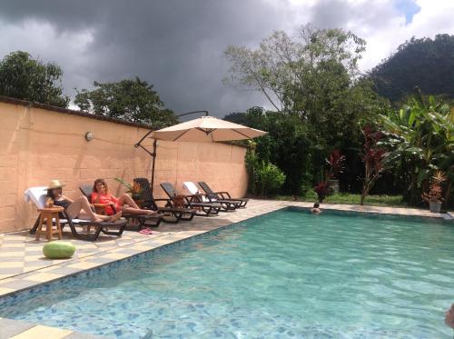 two girls sitting in chairs next to a swimming pool at Casa de Piedra in Mindo