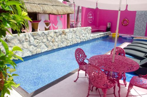 a table and chairs next to a swimming pool at Santuario Playa in Playa del Carmen