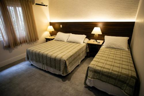 a hotel room with two beds and two lamps at Pousada Aguas Claras in Búzios
