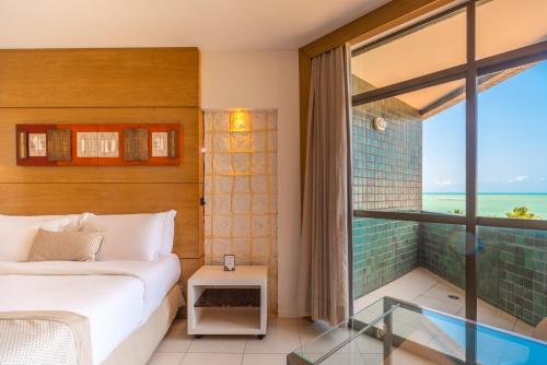 a bedroom with a bed and a large window at Ritz Lagoa da Anta Hotel & SPA in Maceió
