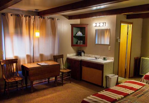 uma casa de banho com um lavatório, uma mesa e uma cama em High Country Motel and Cabins em Cooke City