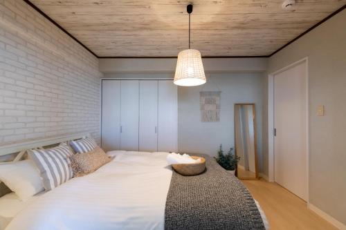 a bedroom with a large white bed and a light fixture at Little Santa in Ginowan