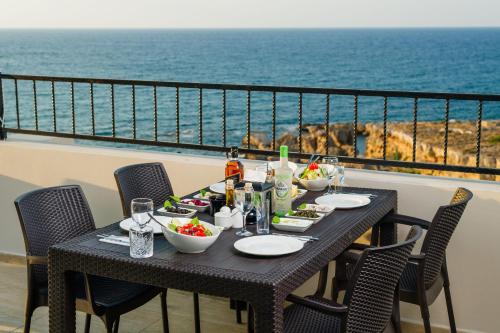 a table with food and drinks on a balcony with the ocean at Olivia Palm Hotel in Kyrenia