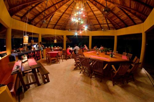 un restaurante con mesas y sillas de madera y un bar en Hotel Vista de Olas, en Santa Teresa Beach