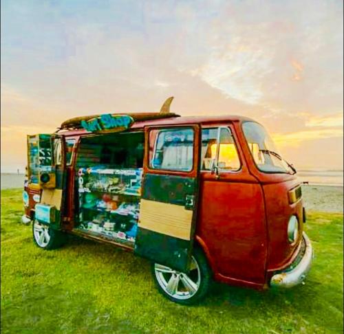 a red van parked on the grass with a surfboard on top at Surf hostel My Friends in Huanchaco