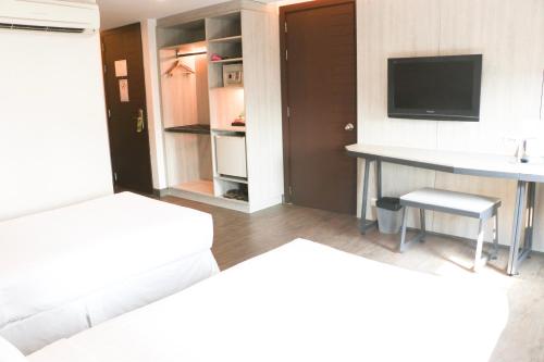 a room with two beds and a desk and a television at The Mini R Ratchada in Bangkok
