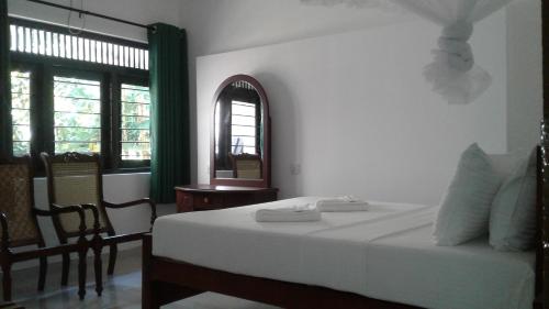 a bedroom with a bed and a chair and a window at Water Front Home Stay and Resort in Anuradhapura