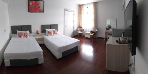 a hotel room with two beds and a desk at Coconut Bay Lodge in Bandar Seri Begawan