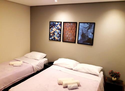 dwa łóżka w pokoju z trzema obrazami na ścianie w obiekcie Royal Ibirapuera Park - Flat w São Paulo