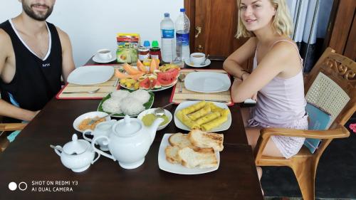 a man and a woman sitting at a table with food at The Wave's Guest House in Mirissa