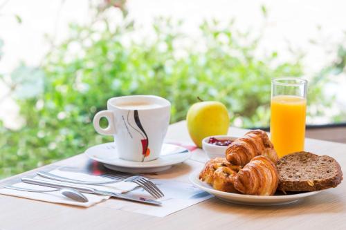 Best Western Armor Park Dinan et Spa في دينان: طاولة مع كوب من القهوة وصحن من المعجنات