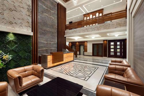 a lobby with two leather chairs and a staircase at Ramada by Wyndham Kapurthala in Kapūrthala