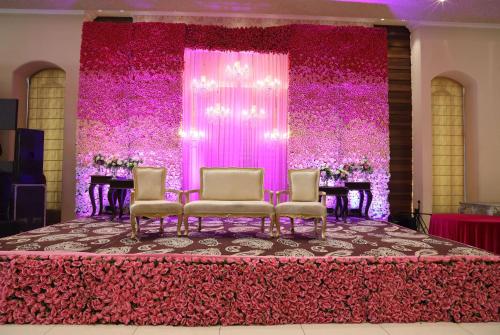 a table with chairs in front of a pink backdrop at Ramada by Wyndham Kapurthala in Kapūrthala