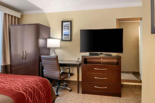 a hotel room with a bed and a desk with a television at Comfort Inn Columbia Gorge in The Dalles