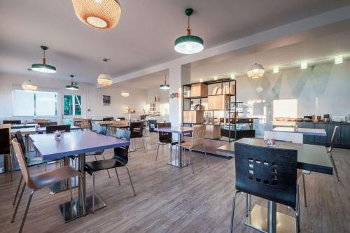 ein Restaurant mit Tischen und Stühlen in einem Raum in der Unterkunft Comfort Hotel Linas - Montlhery in Montlhéry
