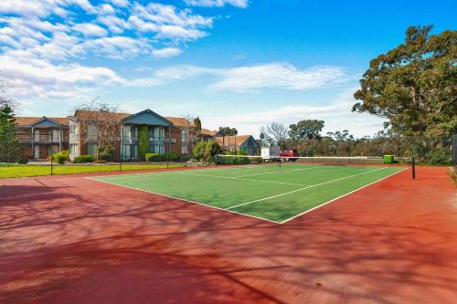 a tennis court in front of a house at Quality Inn & Suites Traralgon in Traralgon