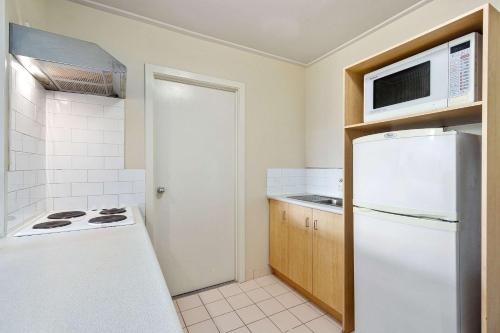 a kitchen with a white refrigerator and a microwave at Knox International Hotel and Apartments in Wantirna