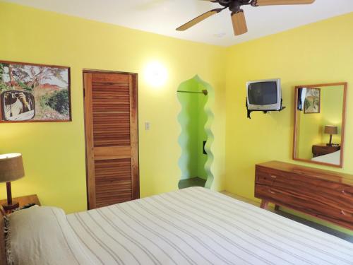 a bedroom with a bed and a tv on the wall at Sunrise Club Hotel in Negril