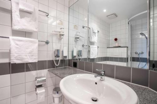 ein weißes Badezimmer mit einem Waschbecken und einem Spiegel in der Unterkunft Quality Hotel & Suites Muenchen Messe in Haar