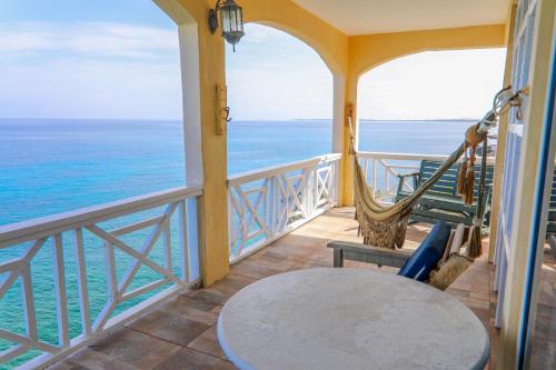 balcón con mesa, sillas y vistas al océano en Home Sweet Home Resort, en Negril