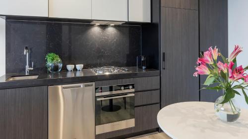 a kitchen with a stove and a table with pink flowers at Avani Melbourne Box Hill Residences in Box Hill