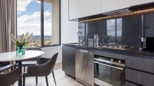 a kitchen with a table and a dining room at Avani Melbourne Box Hill Residences in Box Hill