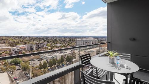 a balcony with a table and chairs and a view of a city at Avani Melbourne Box Hill Residences in Box Hill