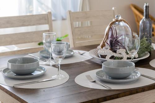 a wooden table with plates and wine glasses on it at Little Santa in Ginowan