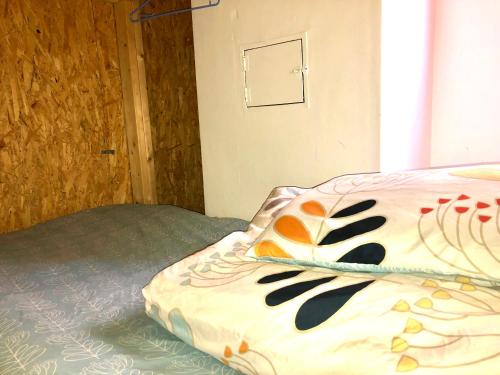 a bed with a comforter on it in a bedroom at Cloud Sharing Hotel Hakata 1 Guesthouse Dormitory in Fukuoka