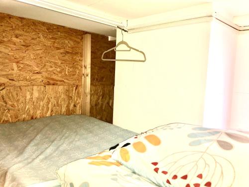 a bed in a room with a wooden wall at Cloud Sharing Hotel Hakata 1 Guesthouse Dormitory in Fukuoka