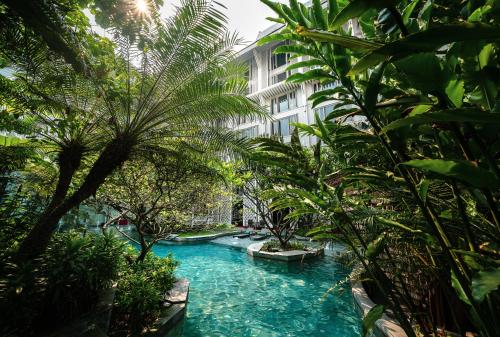 a swimming pool with palm trees and a building at Hua Chang Heritage Hotel in Bangkok