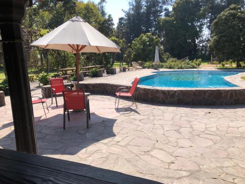 a patio with chairs and an umbrella next to a pool at The White House by Casona Lo Aguirre - El Monte RM in Talagante