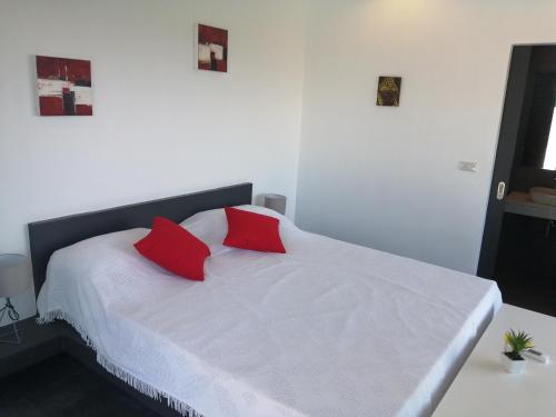 a white bed with two red pillows on it at Pearl Villa in Nathon