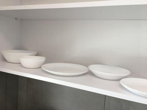four white bowls sitting on a white shelf at Studio Fibra Macchiato in Rybnik