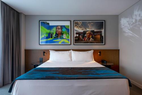 a hotel room with a bed with three pictures on the wall at The Adnate Perth - Art Series in Perth