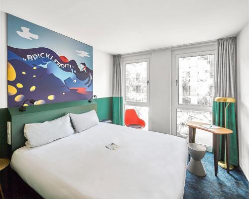 Un dormitorio con una gran cama blanca y una ventana en ibis Styles Pforzheim en Pforzheim