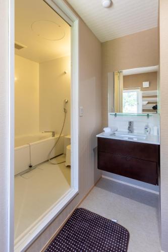 a bathroom with a sink and a tub and a mirror at Cisco Moon in Kutchan