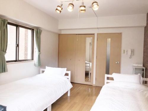 two beds in a room with white sheets at ピオーレ大手門401 in Fukuoka