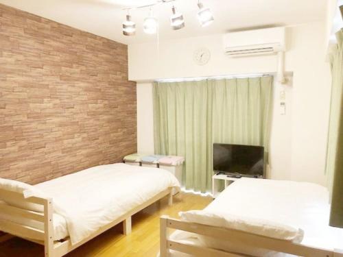 a room with two beds and a television in it at ピオーレ大手門401 in Fukuoka