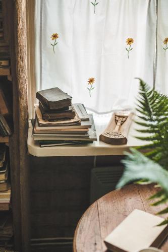 a pile of books sitting on a table next to a window at Pagulbis - Tavo namai in Klabiniai