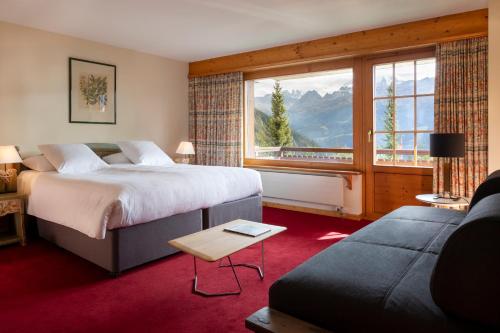ein Hotelzimmer mit einem Bett und einem großen Fenster in der Unterkunft Hotel Montpelier in Verbier