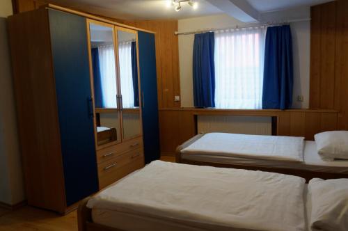 a bedroom with two beds and a cabinet with a mirror at Pension Burger - Bed & Breakfast in Weibersbrunn