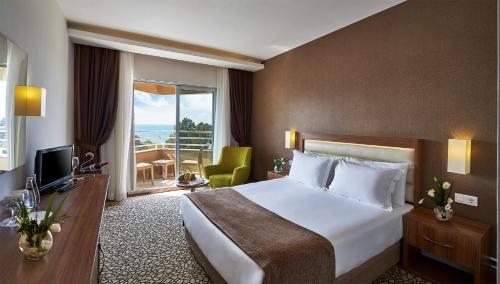 una camera d'albergo con un letto e un balcone di Richmond Ephesus Resort - All Inclusive a Kusadası