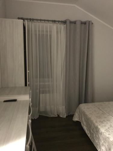 a bedroom with a bed and a window with curtains at Дом in Kyiv